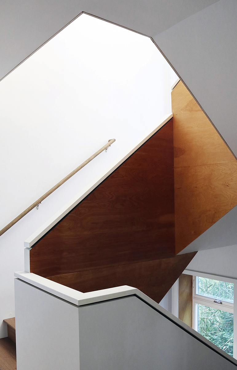 An image of the geometric staircase displaying a contrast between the warm wood-clad paneling and the surrounding white walls.